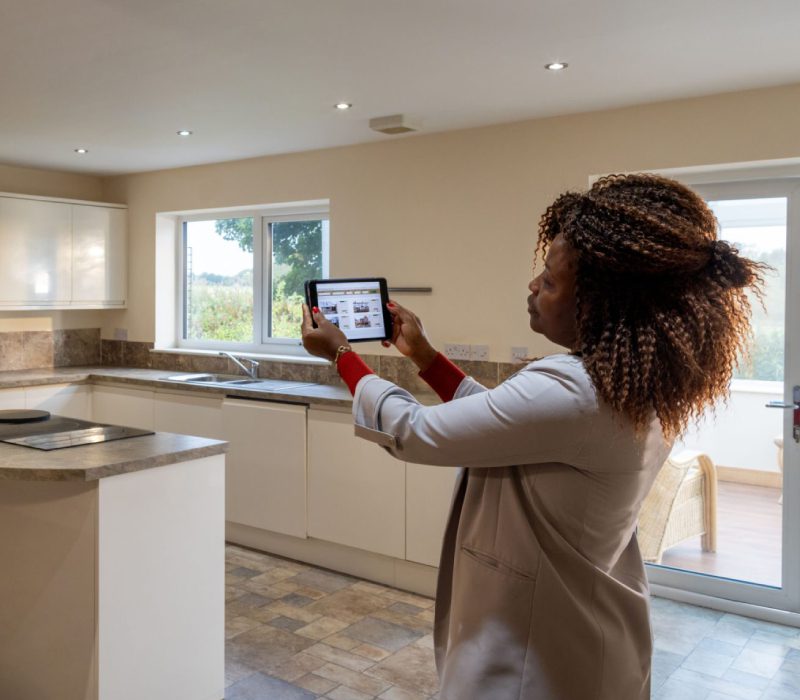 Woman using a tablet to inspect a modern kitchen.