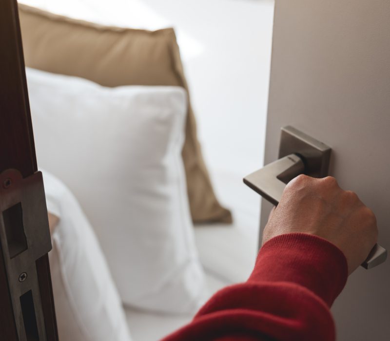 Person opening a hotel room door with keycard.