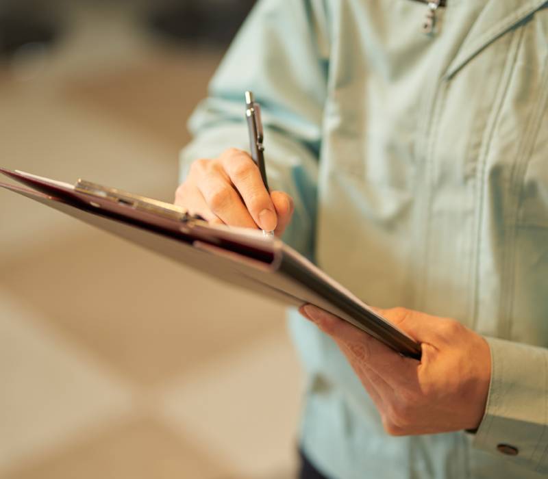 Person writing on a clipboard with a pen.