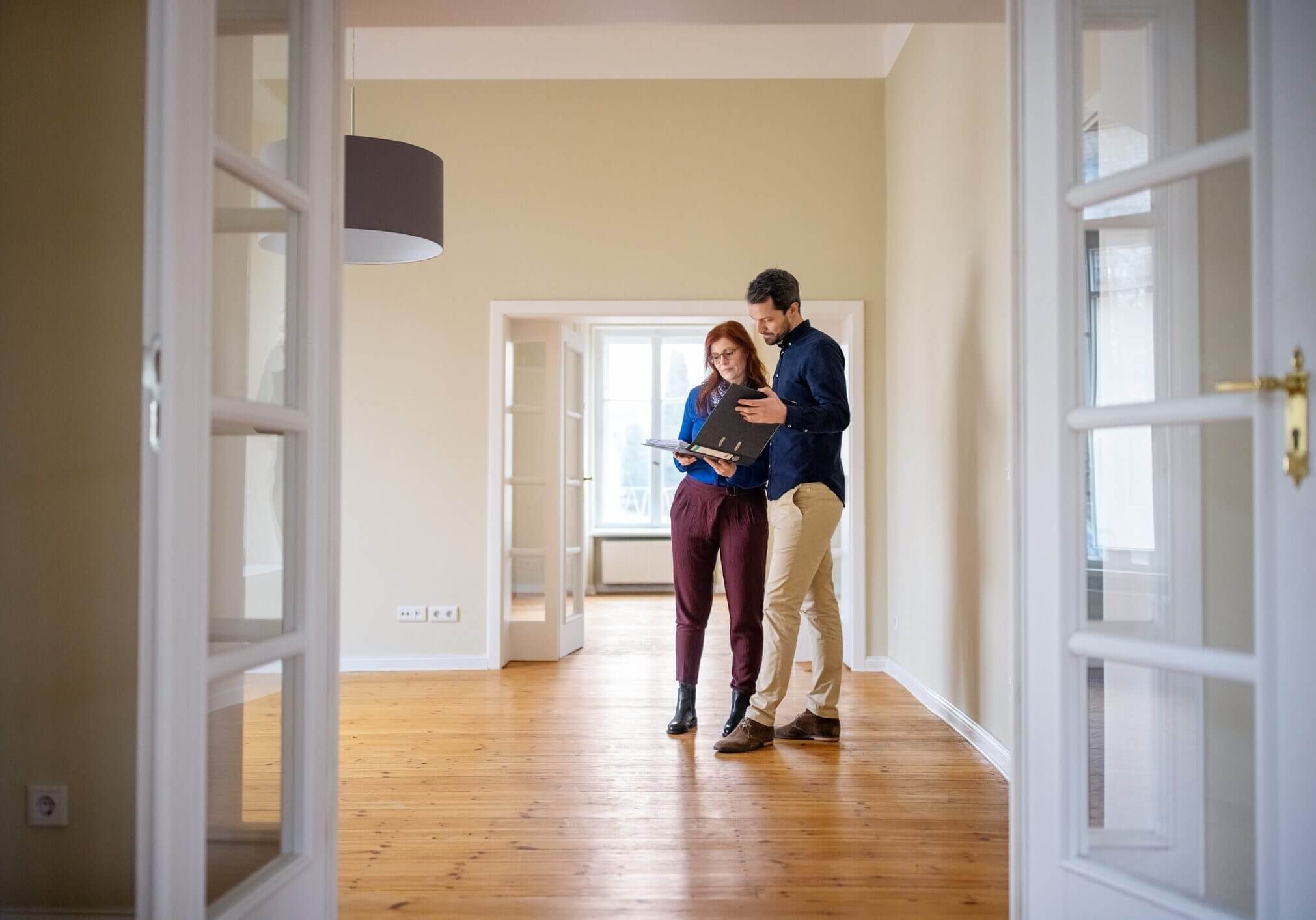 Couple embracing in a bright, empty room with wooden floors.